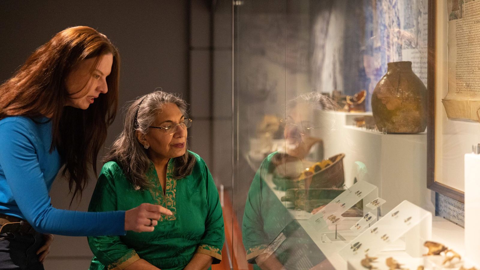 Two ladies looking at artefacts in a cabinet at Carrickfergus Museum
